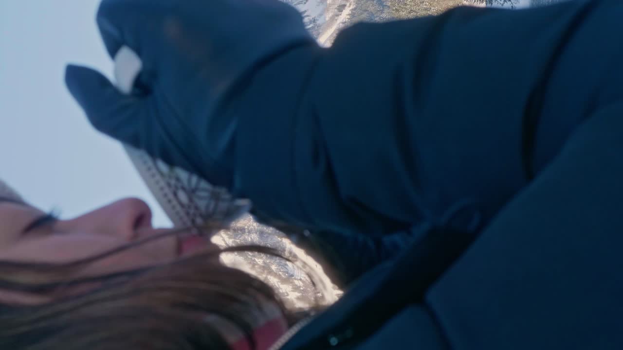 Young tourist woman drinks a warm cup of coffee in alpine Switzerland landscape. Vertical video.