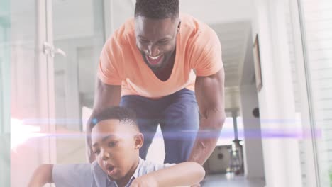 animation of lights over happy african american father and son having fun at home