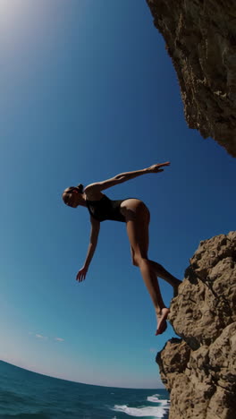 woman cliff jumping into the ocean
