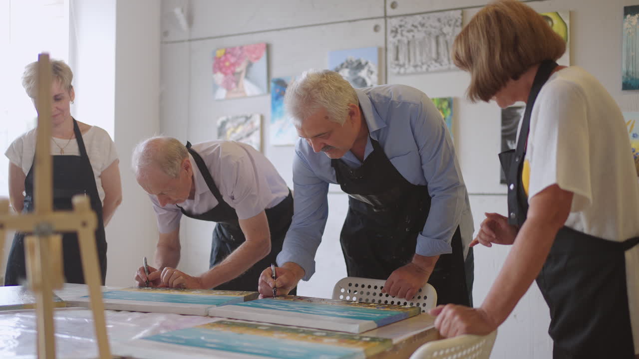 счастливая группа друзей сенио люди рисуют картины вместе в классе. обсуждают и смеются вместе