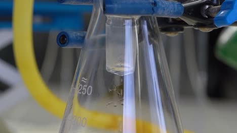 equipo de química científica en un laboratorio médico mientras el líquido gotea en un matraz