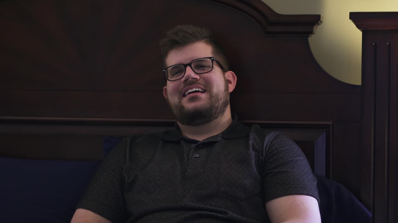 hombre hablando y riendo mientras está acostado en la cama jugando videojuegos con amigos