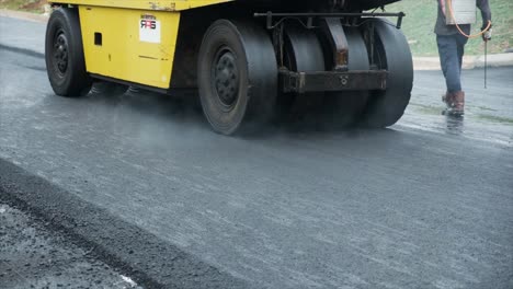 process of asphalting road construction infrastructure by compressing, compacting, leveling and smoothing the asphalt road surface using a pneumatic tyred roller