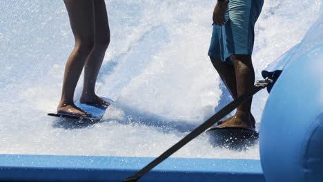 Instructor-helping-a-girl-surf-on-a-wave-machine,-CLOSE-UP