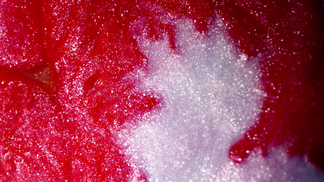 Red and white substances blend in a swirling abstract pattern, captured in a vivid macro close-up
