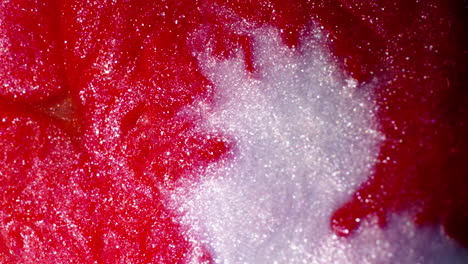 red and white substances blend in a swirling abstract pattern, captured in a vivid macro close-up