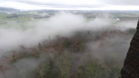 static shot of fog rolling in over the forest towards the wallace monument in stirling