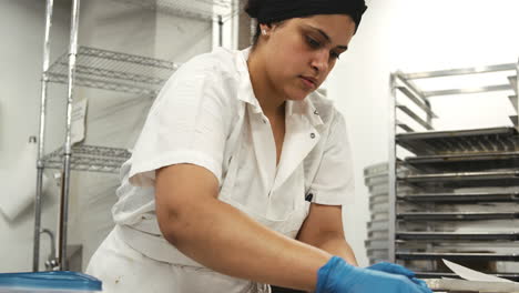 Hispanic-woman-cutting-cookie-dough-at-a-bakery,-close-up