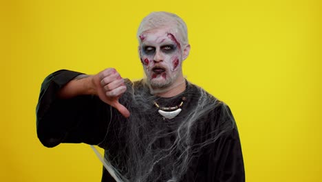 hombre siniestro halloween zombi mostrando pulgares hacia abajo gesto de señal, desaprobación, insatisfecho, disgusto