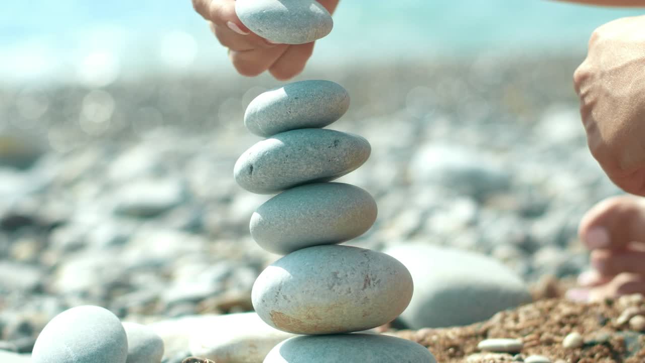 Woman hand building pebbles tower on beach during holidays. Relax on sea beach