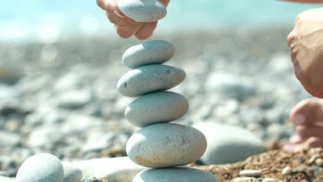 woman hand building pebbles tower on beach during holidays. relax on sea beach