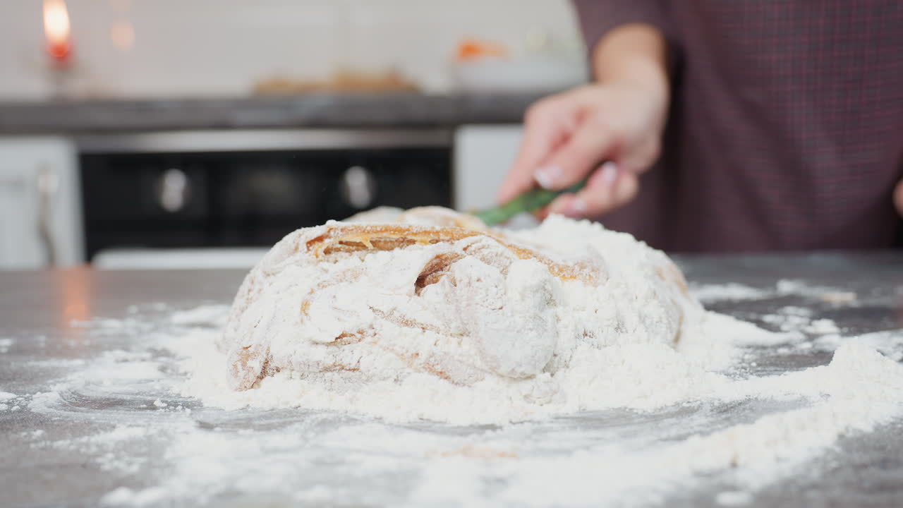 주방 카운터에서 밀가루와 밀가루를 고 는 마론 옷을 입은 사람의 클로즈업, 손이 적극적으로 재료를 는, 밀가루로 은, 부드러운 밀가루가 베이킹을 위해 모양을 습니다.