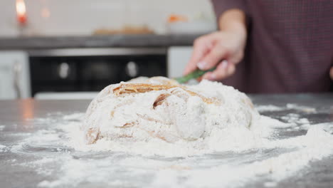primer plano de una persona en tela marrón amassando y mezclando la masa con harina en la encimera de la cocina, las manos mezclando activamente los ingredientes, salpicadas de harina, mientras la masa suave toma forma para hornear