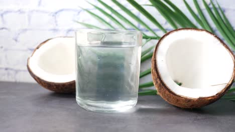 coconut water in a glass with coconut pieces and palm leaf