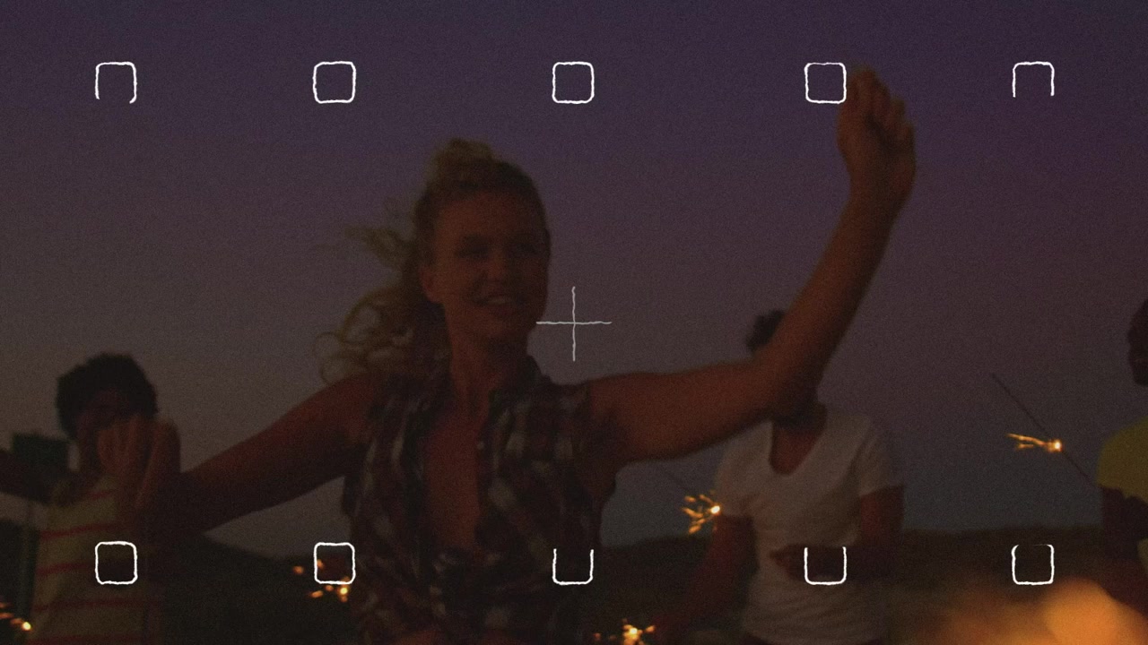 Gruppo di amici eterogeneo che festeggia con stelline luminose al tramonto