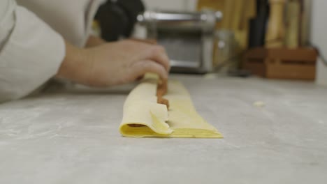 chef rolls lasagna dough with sauce ingredients inside