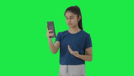 Serious-Indian-teenage-girl-talking-to-someone-on-video-call-Green-screen