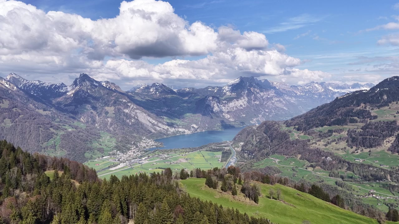 Riprese con drone che mostrano un suggestivo lago alpino circondato dalle maestose Alpi svizzere sotto nuvole imponenti.