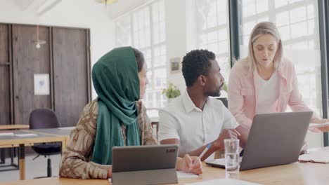 busy diverse business people discussing work at table with laptop in office in slow motion