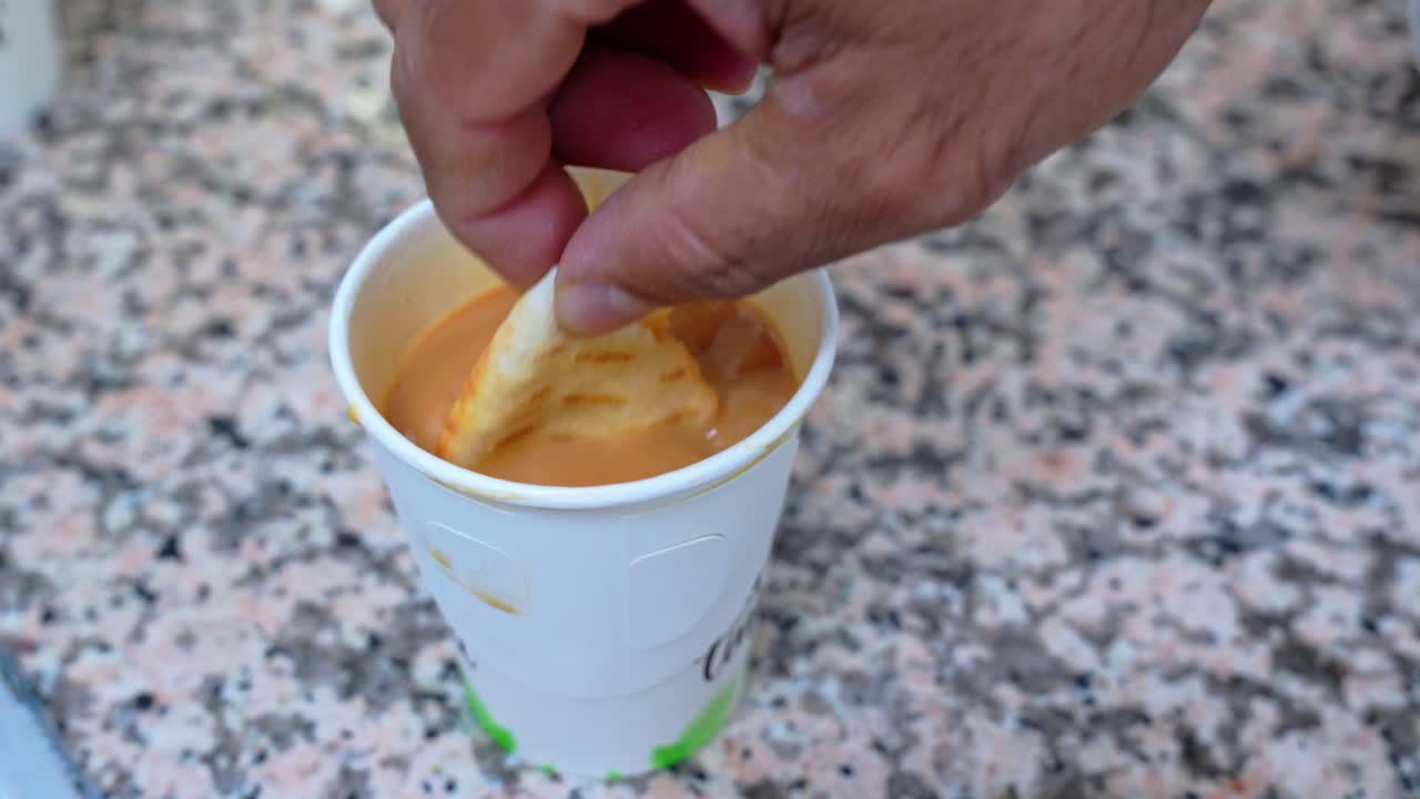 Warm, inviting close-up of a biscuit dipped into chai—perfect for food, culture, lifestyle, or cozy moment themes