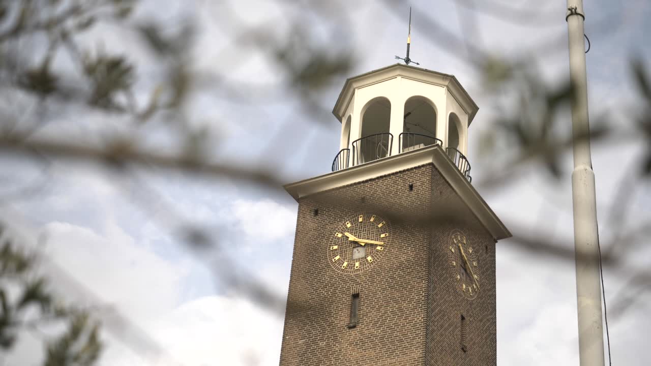 An old Clock Tower in Watergraafsmeer, Amsterdam, With Tree Branches Swaying in the Foreground