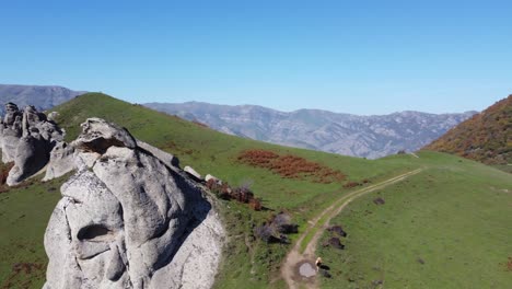 el ganado pasta en las laderas de las montañas verdes exuberantes cerca de los afloramientos de granito