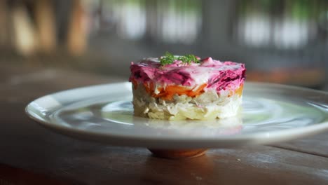 ensalada rusa tradicional con remolacha y verduras de arenque, en una mesa de madera en un plato blanco