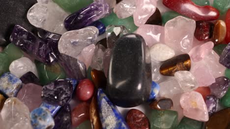 chakra stones rotate on a vibrant bed of various gemstones, showcasing their colors and textures under soft lighting