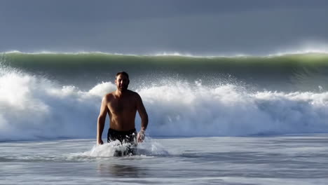 Man on a beach with a large wave