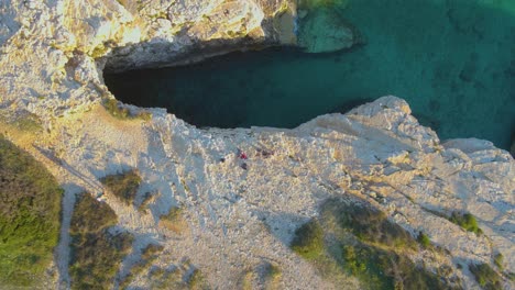 Visitors-stand-at-the-precipice-of-the-diving-spot,-enjoying-the-vista-of-the-sea's-crystal-clear-water