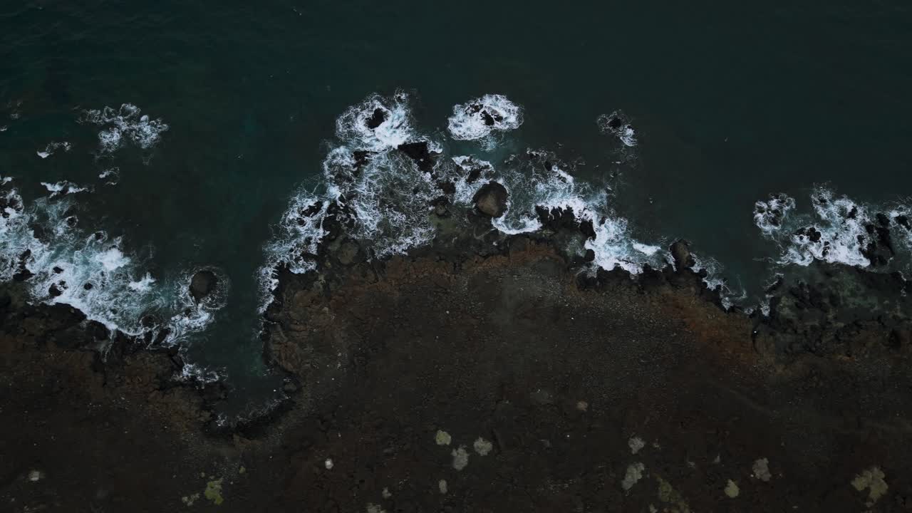 Aerial View of Dark Blue Ocean Waves Crashing on Rocky Shoreline in Orzola Lanzarote Canary Islands Spain Coastal Scenery and Volcanic Landscape