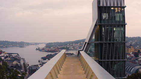 flying over empty viewpoint towards glass lift overlooking arendal town houses and church in norway