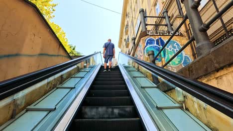 hombre monta escaleras mecánicas al lado de la pared cubierta de graffiti