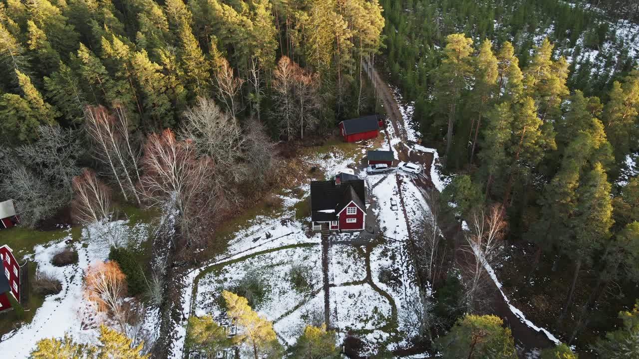 Beautiful aerial of a small red Swedish cabin surrounded by forests in remote and rural Sweden