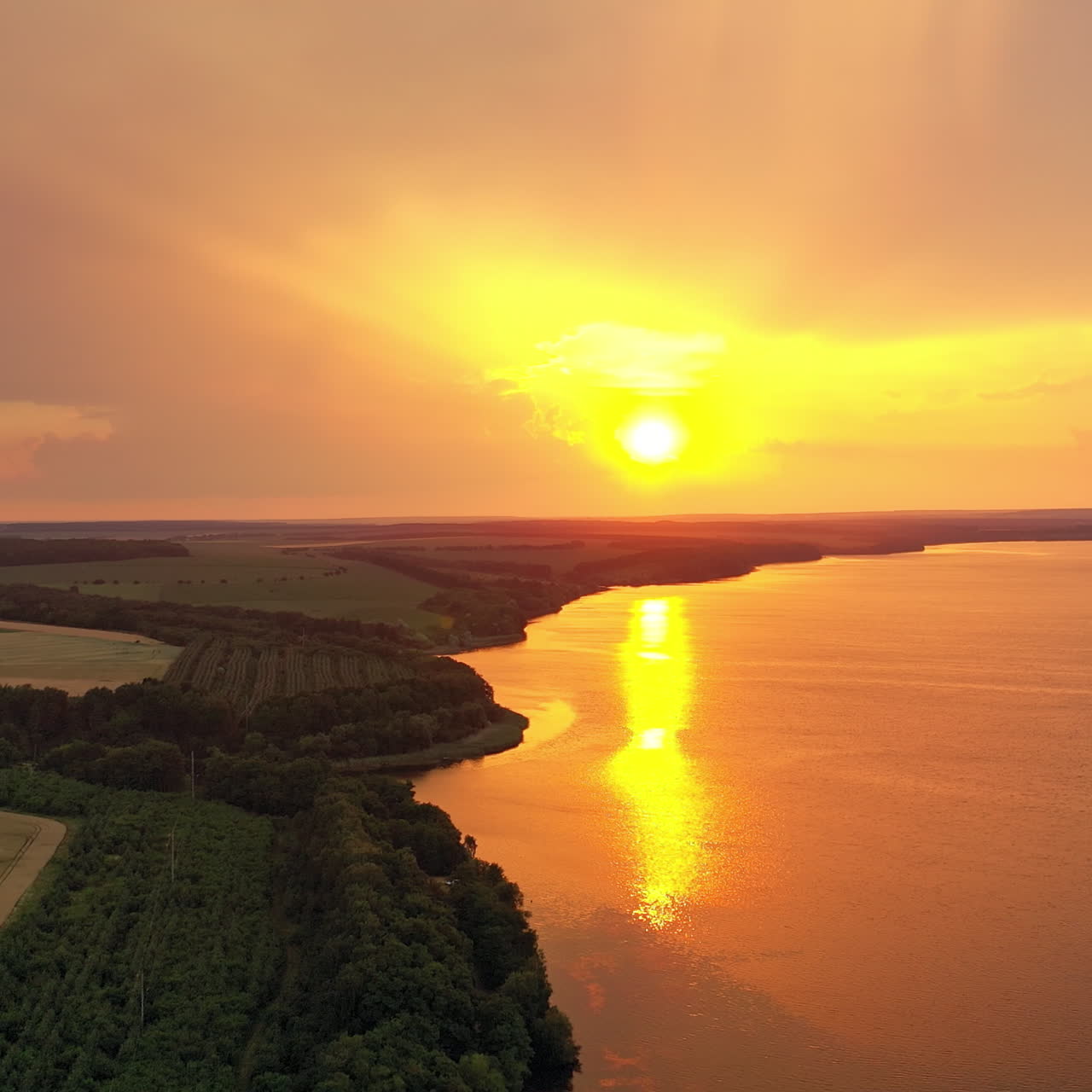 Fantastic sunset. Golden reflection of the evening sun in the water. Aerial view of the beautiful river on the natural background at sunset.