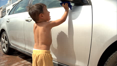 Cámara-Lenta-De-Un-Joven-Latino-Mexicano-Sin-Camisa-Concentrado-En-La-Limpieza-Detallando-El-Auto-Familiar-En-Un-Día-Soleado