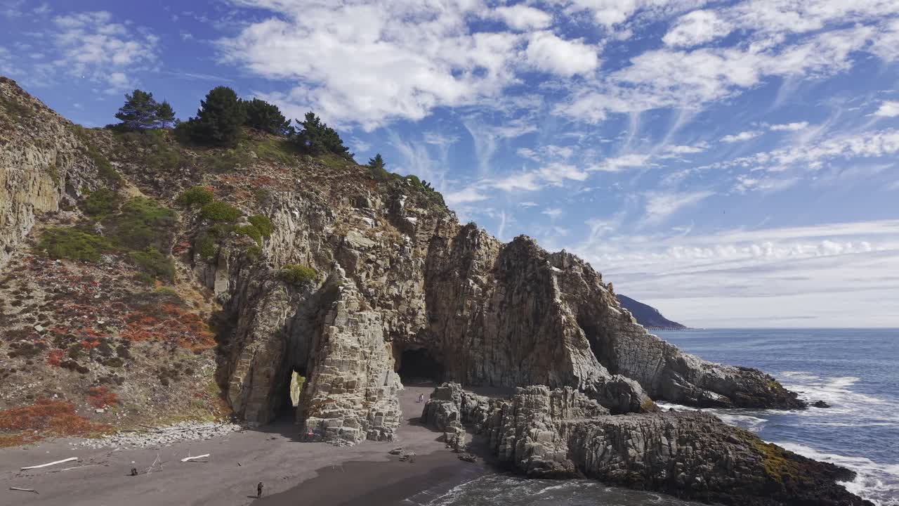 Volando verso Piedra del Elefante a Constitución sopra l'acqua aperta con le onde che si infrangono verso una riva di sabbia scura in Cile, 4K.