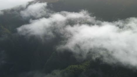 volando sobre las nubes sobre una montaña verde