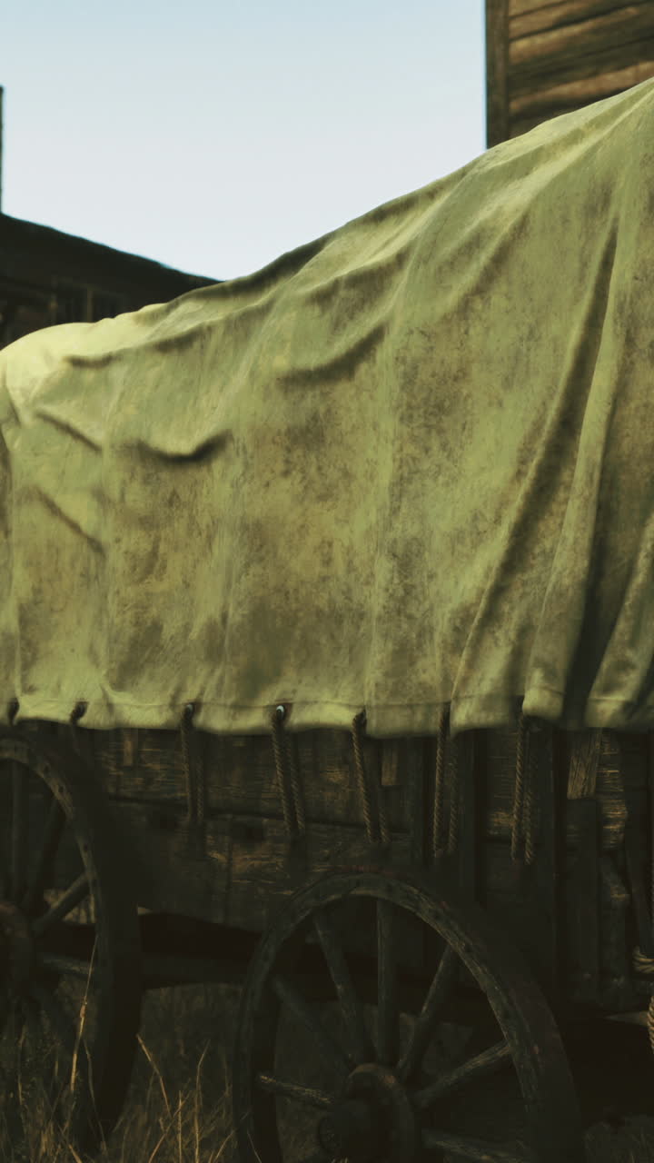 Old wooden wagon covered with fabric in a deserted town during sunset