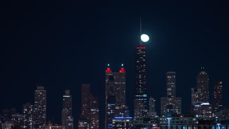 Medium-shot-of-near-full-moon-rising-behind-and-over-the-Northside-of-the-Chicago-skyline-at-night-time-lapse