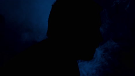 silueta de un hombre inhalando y exhalando humo de un vaporizador