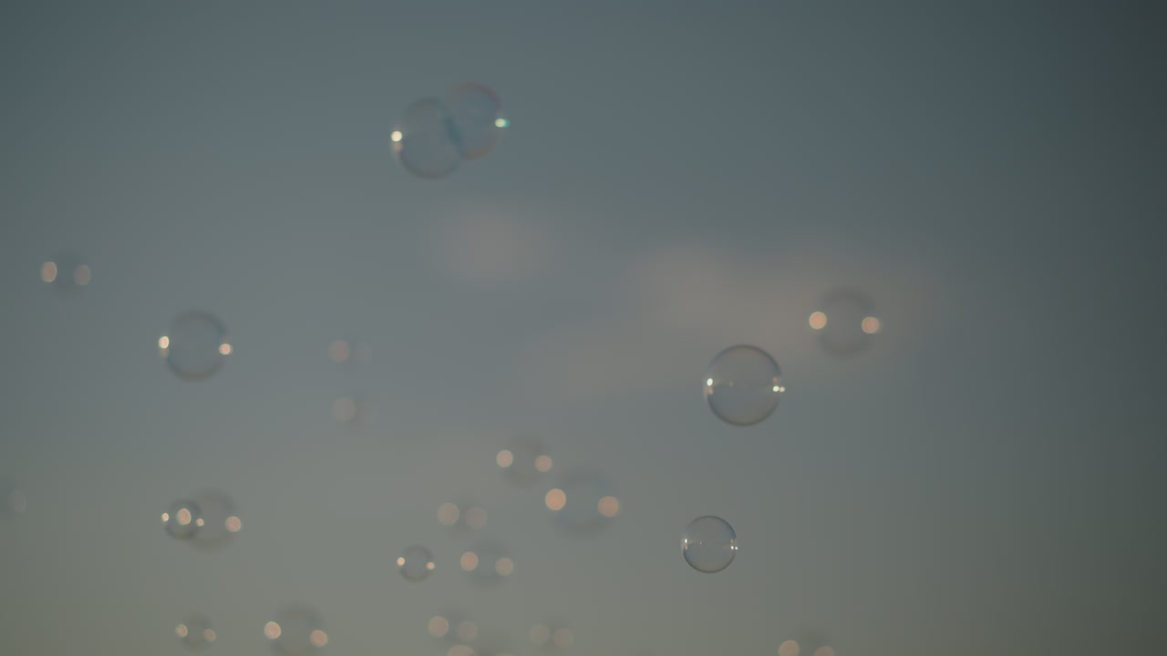 Close-up of bubbles floating in the air against a clear sky. The bubbles reflect light, creating a dreamy, whimsical scene of a simple joy and beauty of bubbles drifting freely in the open air