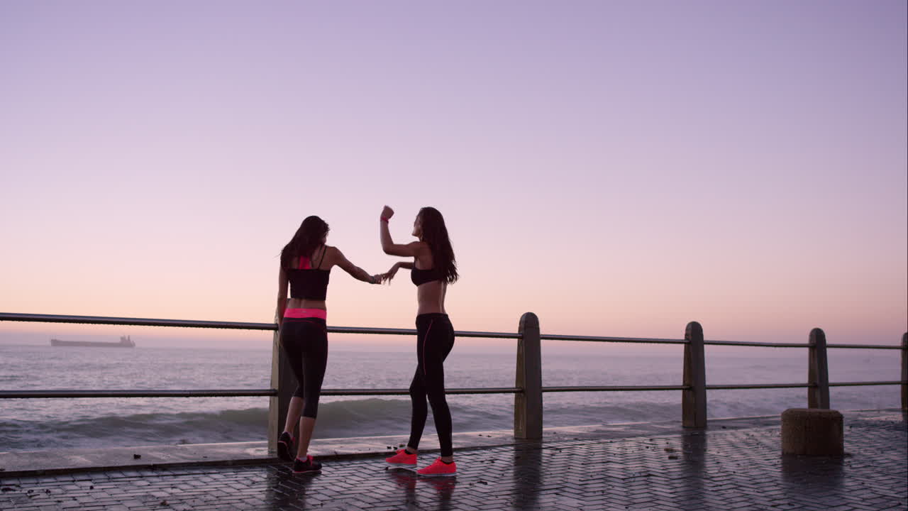 두 명의 운동선수 친구들은 해가 지는 동안 달리기를 끝내서 행복합니다.