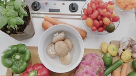 Overhead-view-of-bowls-and-various-chopped-vegetables-on-kitchen-countertop,-slow-motion