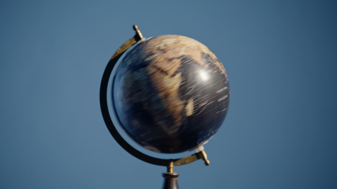Hand spinning vintage globe on blue background closeup. Traveler rotating Earth