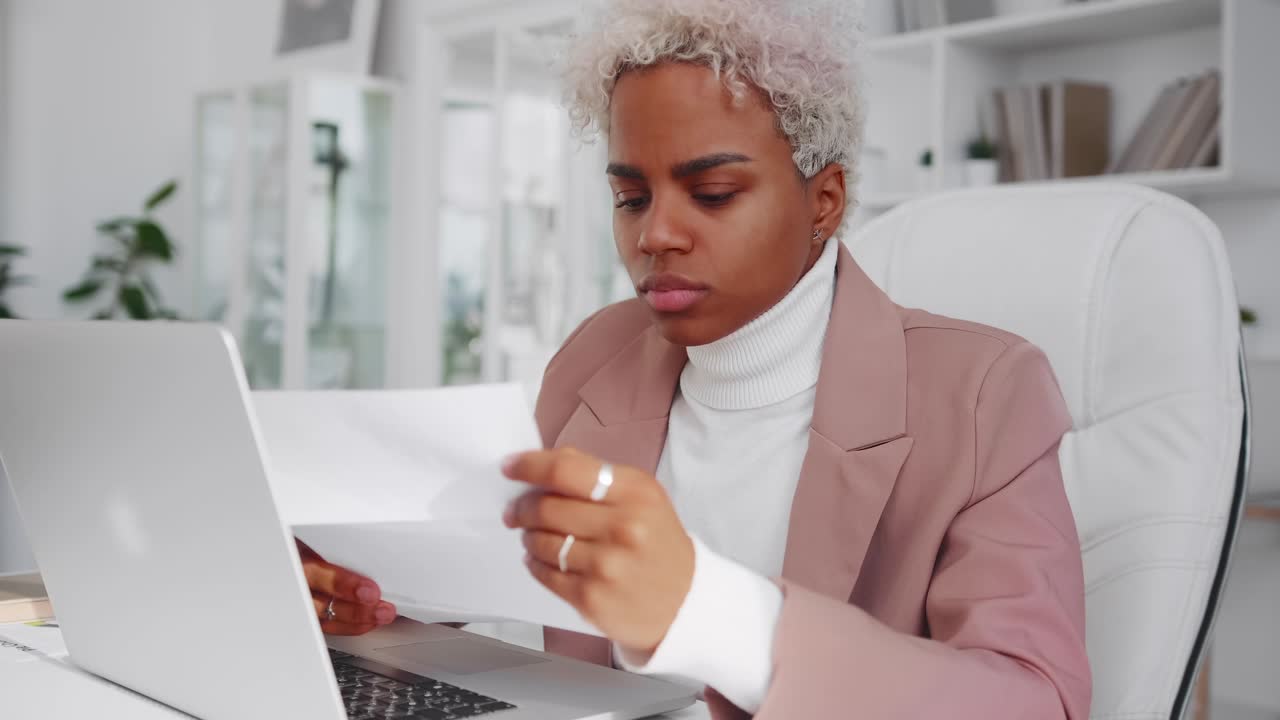 Successful african american woman reads something from sheet of paper and sighs