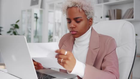 successful african american woman reads something from sheet of paper and sighs