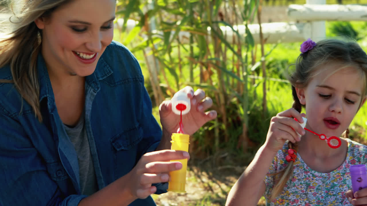 madre e hijos soplando burbuja en el parque 4k
