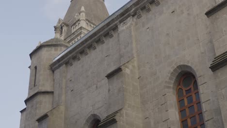 exterior of medalla milagrosa church in ecuador with windows panning up to the spire with cross against blue skies