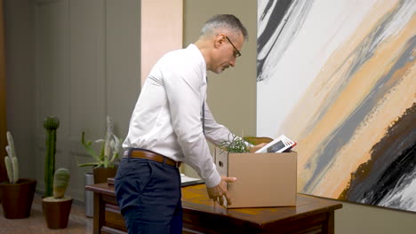 mature man thinking about the resignation and leaving the office with his supplies in a box